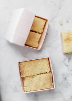 two pieces of cake in a box on a marble counter top next to another piece of cake