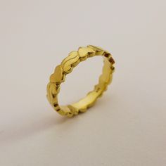 a yellow gold ring with wavy edges on a plain surface, ready to be worn