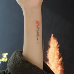 a woman's arm with a small flower tattoo on the left side of her wrist