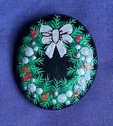 a painted rock with a bow and pineconis on it sitting on a blue surface