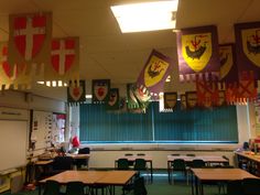 a classroom filled with lots of desks and flags hanging from the ceiling above them