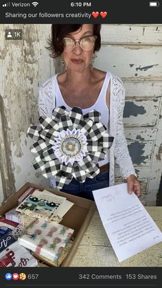 a woman holding up a paper flower in front of an open box with papers on it