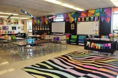 an empty classroom with zebra rugs and tables in the middle is decorated with bright colors