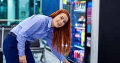 a woman with long red hair leaning against a vending machine