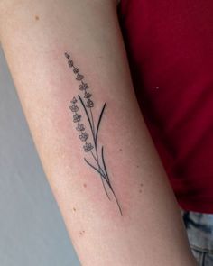 a woman's arm with a small flower tattoo on the back of her left arm