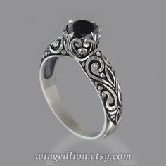 a black diamond engagement ring with filigrees and scrolls on the sides, set in