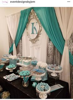 a table topped with blue and white desserts next to a curtained wall covered in sequins