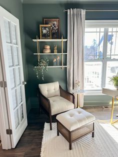 a living room with a chair, ottoman and shelves on the wall in front of a window