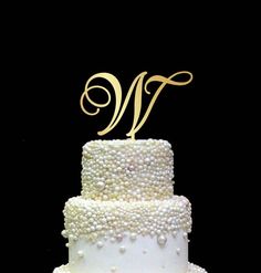 a wedding cake with pearls and a monogram on top