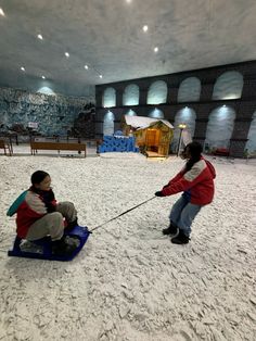 two children playing in the snow on sleds with one child pulling them behind