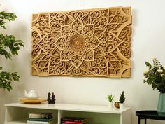 a wooden wall hanging over a white shelf next to a potted plant and books