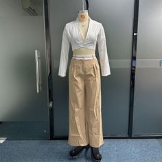 a mannequin is dressed in beige pants and a white shirt