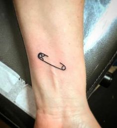 a small black arrow tattoo on the wrist