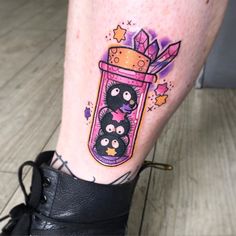 a woman's leg with an image of cats in a jar tattoo on it