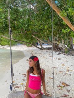 a woman sitting on a swing at the beach