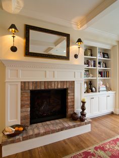 a living room with a fire place and bookshelves on the wall above it