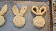 three dough buns shaped like rabbits on a baking sheet, ready to go into the oven