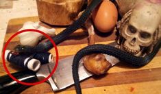 a knife on a cutting board next to a skull and an egg in a bowl