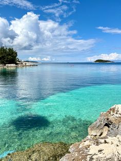 the water is crystal blue and clear with some rocks in front of it on an island