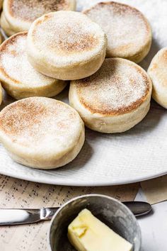 some pancakes and butter on a plate with a bowl full of butter next to it