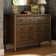 a dresser with two lamps and pictures on it