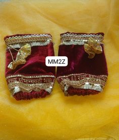 two pairs of red velvet shoes with gold decorations on them, sitting next to each other