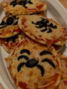 four pizzas with black olives and cheese on a plate