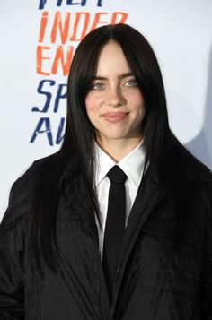 a woman with long black hair wearing a suit and tie