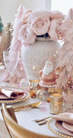 there is a table set with pink flowers and gold place settings for the holiday dinner