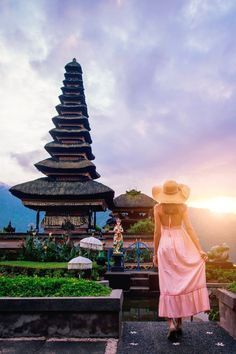 a woman wearing a hat standing in front of a pagoda