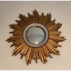 a gold sunburst mirror mounted on the wall