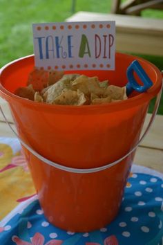 an orange bucket filled with food sitting on top of a table