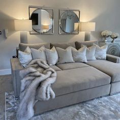 a living room with a large couch and mirrors on the wall above it's headboard