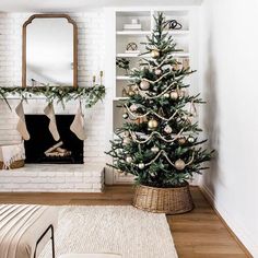 a living room decorated for christmas with a tree in the corner and stockings on the fireplace