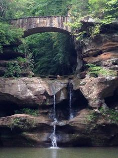 a waterfall with a stone bridge above it