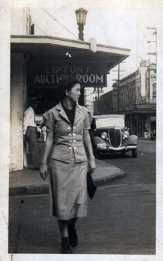 an old photo of a woman walking down the street