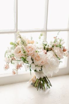 a bouquet of white and pink flowers sitting on a window sill next to a window