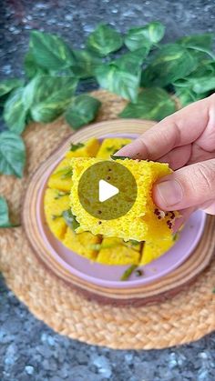 a person holding a piece of food in front of a plate with leaves on it