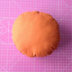 an orange pillow sitting on top of a cutting board next to a ruler and scissors