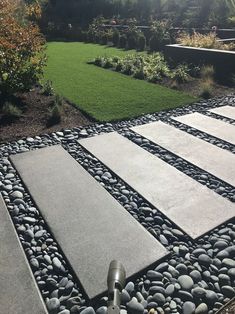 an outdoor walkway made out of stones and gravel in the middle of a garden area