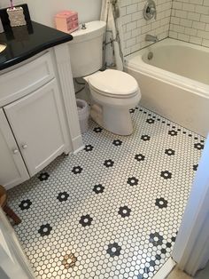 a white toilet sitting next to a bath tub under a bathroom sink with black and white tiles