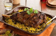 a large roasting pan filled with meat and rice on top of a wooden table