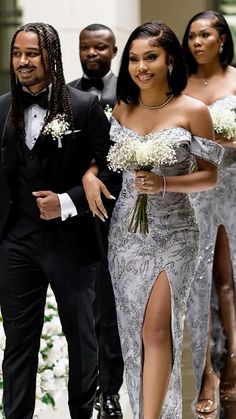 two women in dresses walking down the aisle with one man wearing a tuxedo