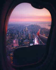 the view from an airplane window looking down on a cityscape at dusk and sunset