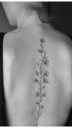 the back of a woman's shoulder with a flower tattoo on her left side