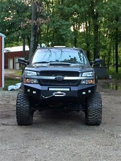 a black truck parked in front of a red building with trees and grass around it