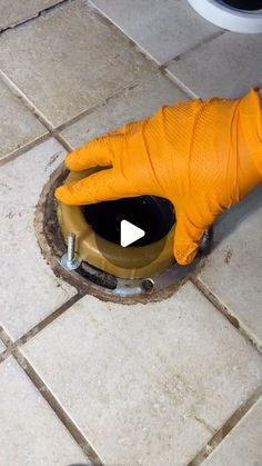 a person in orange gloves is cleaning a hole