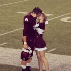 two people in football uniforms kissing on the field