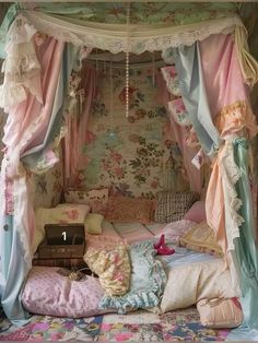 a canopy bed with pink and blue drapes on it's sides, surrounded by floral wallpaper