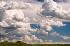 the sky is filled with clouds and green hills